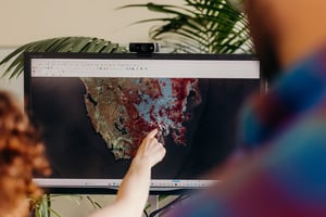 Geoneon analysts reviewing a satellite-derived map of Tasmania on a workstation.